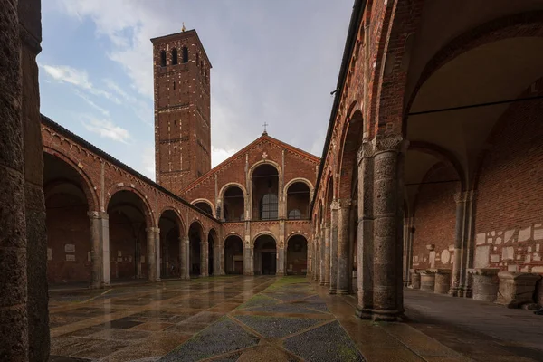 Saint Ambrogio kilise tuğlası bina çan kuleleri, avlu, kemerler, mavi gökyüzü ve bulutlar, Milan, Lombardy, İtalya