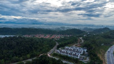 Yeşil asfalt yolu olan yerleşim alanının havadan görüntüsü ve görüş açısının hemen üstündeki evler. Banliyö ve şehir merkezi manzarası. Emlak ve konut piyasası kavramı.
