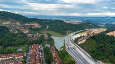 Yeşil asfalt yolu olan yerleşim alanının havadan görüntüsü ve görüş açısının hemen üstündeki evler. Banliyö ve şehir merkezi manzarası. Emlak ve konut piyasası kavramı.