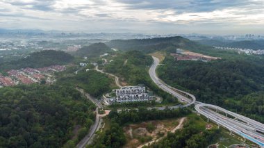 Yeşil asfalt yolu olan yerleşim alanının havadan görüntüsü ve görüş açısının hemen üstündeki evler. Banliyö ve şehir merkezi manzarası. Emlak ve konut piyasası kavramı.