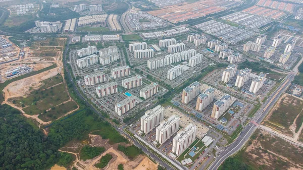 Yeşil asfalt yolu olan yerleşim alanının havadan görüntüsü ve görüş açısının hemen üstündeki evler. Banliyö ve şehir merkezi manzarası. Emlak ve konut piyasası kavramı.
