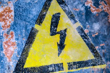 Duvarında siyah bir ok olan sarı yüksek akım tehlike işareti