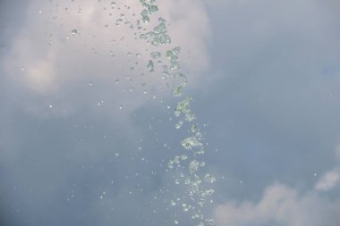 Gökyüzünün arka planındaki çeşmeden fışkıran su.