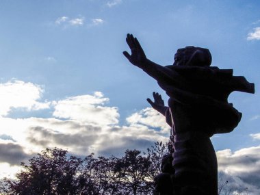 Kaldırılmış elleri olan bir kadının silueti.