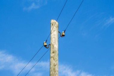 Gökyüzü arka planında radyo iletim hatları olan tahta bir direk.