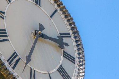 Parktaki bir sokak saatinin metal kadranı ve sandalyeleri