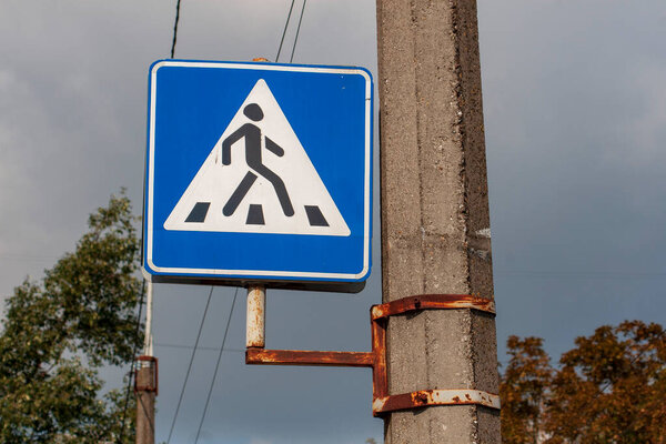 Blue and white road sign on a pedestrian crossing