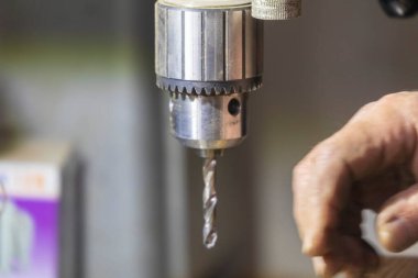Delme makinesi çalışıyor. Usta atölyede atölye çalışması yapar.
