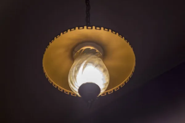 黑暗房间的天花板上挂着一盏灯发出的光 — 图库照片