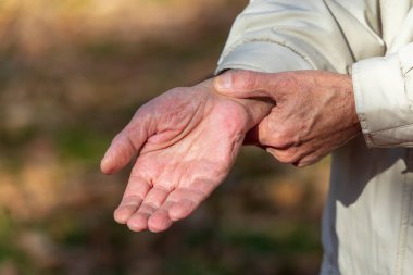 Yaşlı bir adam parkta kalp atışlarını ölçer.