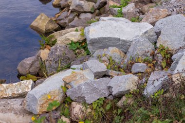 Gölün kenarında büyük gri-sarı taşlar.