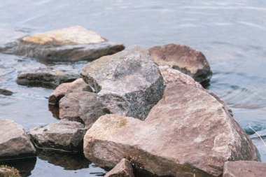 Gölün kenarında büyük gri-sarı taşlar.
