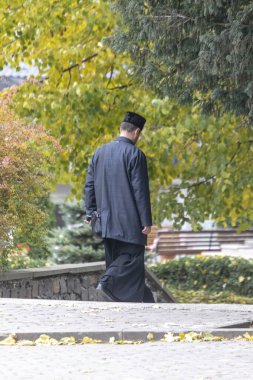 Siyah cüppeli bir rahip parktan kiliseye doğru yürür.