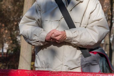 Adam parkta donduğu için ellerini ısıtıyor.