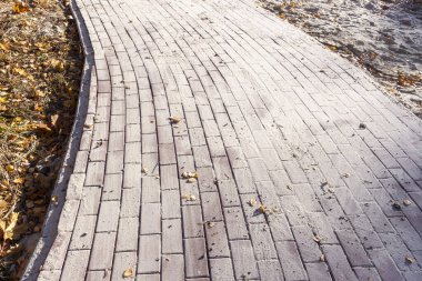 Yol kenarında kumlu, yeni bırakılmış kaldırım taşları.