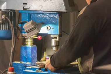 Delme makinesi çalışıyor. Usta atölyede atölye çalışması yapar.