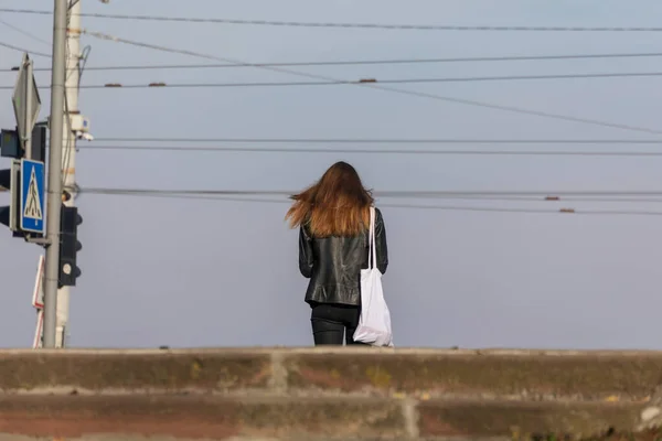 一个长头发的女孩站在斑马附近的红绿灯前 — 图库照片