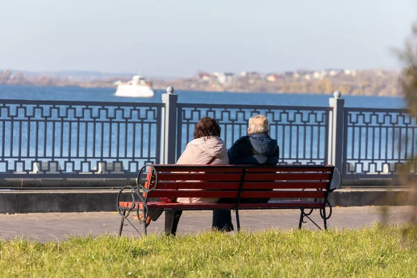 老人和妇女坐在湖边的一条公园长椅上 — 图库照片
