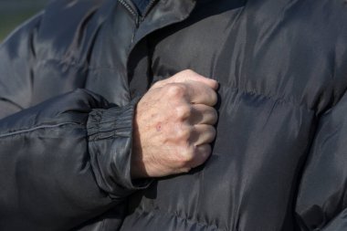 Marş performansı sırasında kalbin üzerine uzanmış bir elin hareketi. Yaşlı adamın eli.