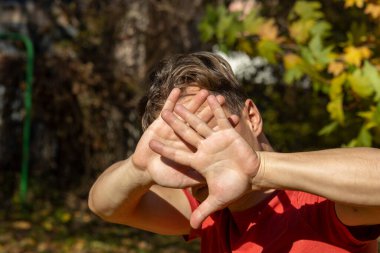 Adam elleriyle yüzünü kapatıyor ve kendini savunuyor.