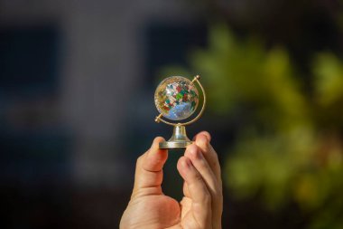 Bir adam elinde küçük renkli bir küre tutuyor.