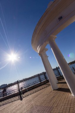 Sonbaharda deniz kıyısındaki gölde sütunları olan beyaz çardak.