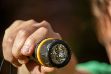 Adamın elinde siyah bir fener var.