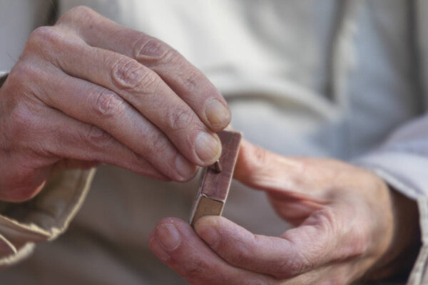 Мужчина зажигает спичку в парке, чтобы зажечь сигарету