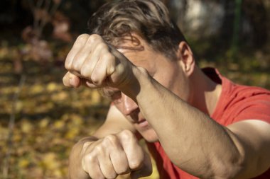 Adam yumruklarını gösteriyor ve soygunculardan korunmak için dövüşüyor.