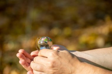 Bir adam elinde küçük renkli bir küre tutuyor.