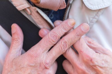 Yaşlı bir adam parmaklarını çapraz yapıp hapis taklidi yapıyor.