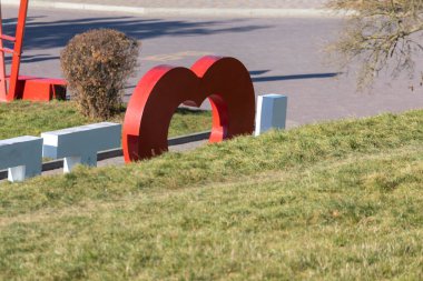 Parktaki büyük metalik kırmızı kalp, aşıkların sembolü.