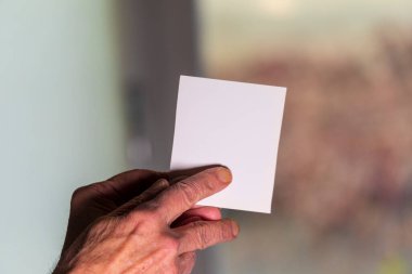 Elinde beyaz bir sayfa kağıt tutan bir adam. Beyaz kağıda metin yazmak için şablon