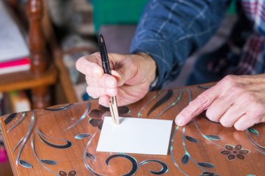 Adam bir kağıt parçasına mürekkep kalemiyle bir şeyler yazacak.