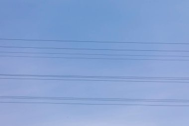 Mavi gökyüzünün arka planındaki elektrik kabloları