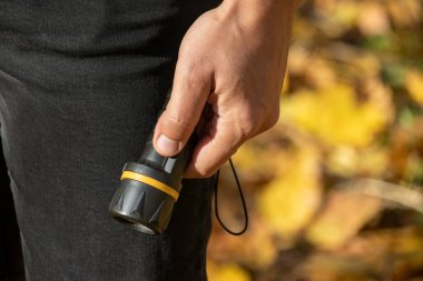 Adamın elinde siyah bir fener var.