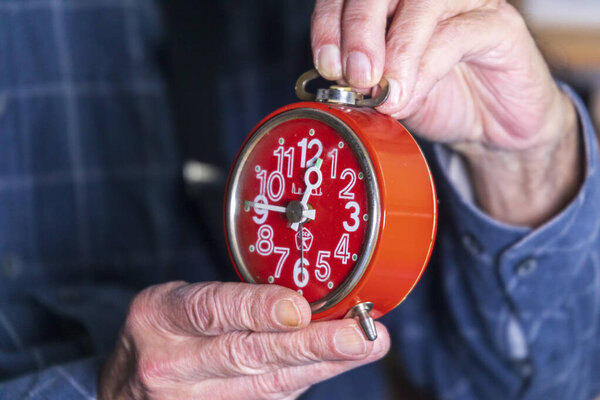 Старик держит красные механические часы