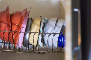 Mutfaktaki rafta renkli seramik tabaklar var.