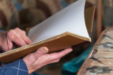 Adamın elinde eski bir kitap var.