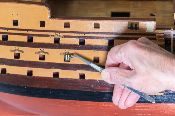 Old man working on creating a ship model