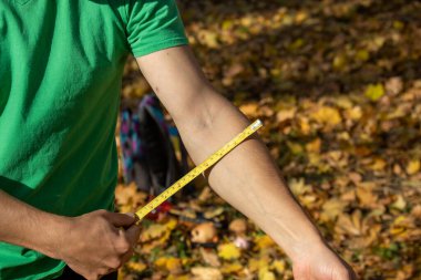 Bir adam uzunluğunu ölçmek için sarı bir mezura tutar.