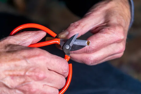 A man holds scissors and a cigarette in his hand, he tries to cut it to quit smoking