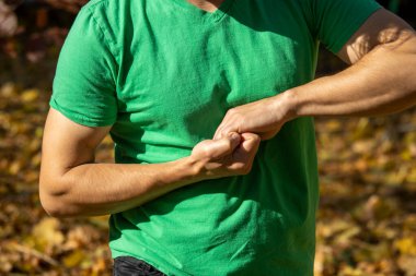 Yeşil tişörtlü bir adam ellerini kilitte tutuyor.