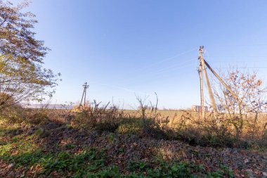 Gökyüzünün arkaplanındaki ufuk çizgisindeki elektrik iletimlerinin kablolu hatları