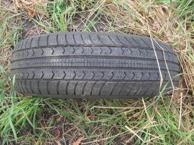 Çimlere dökülen bir araba tekerleğinden siyah lastik.