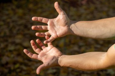 Adam elleri ve parmaklarıyla çeşitli jestler gösteriyor.