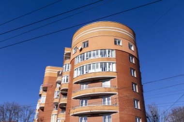 Sarı tuğladan yapılmış yarı dairesel bir ev. Evin ve pencerelerin önünde.