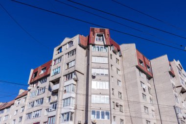 Beyaz tuğladan yapılmış çok katlı bir ev. Evin ön cephesi ve balkonlu pencereler