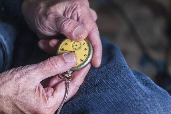 Мужчина держит старинные карманные часы. Символ прошедшего времени