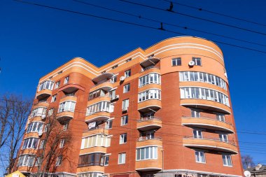 Sarı tuğladan yapılmış yarı dairesel bir ev. Evin ve pencerelerin önünde.